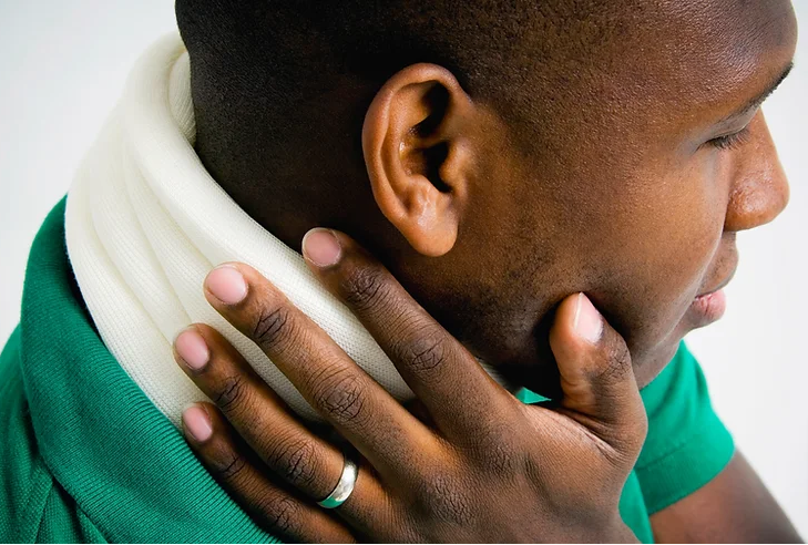 A person wearing a neck brace is touching their jawline, possibly indicating neck discomfort or injury.